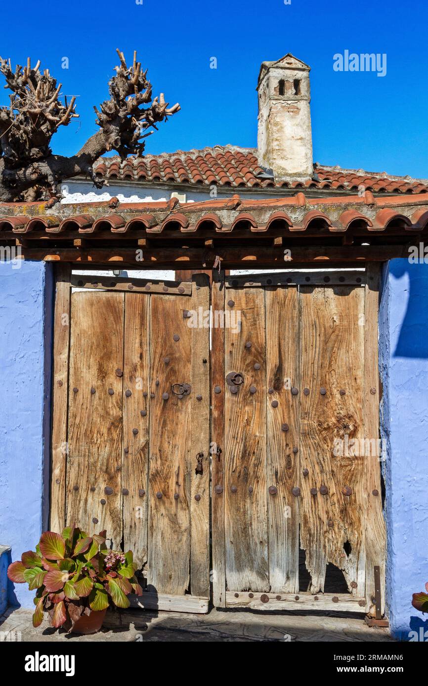 Traditionelles Landhaus mit einer alten Holztür, violetter Wand und Ziegeldach mit einem alten Kamin, im Dorf Ampelakia, Larissa, Griechenland. Stockfoto
