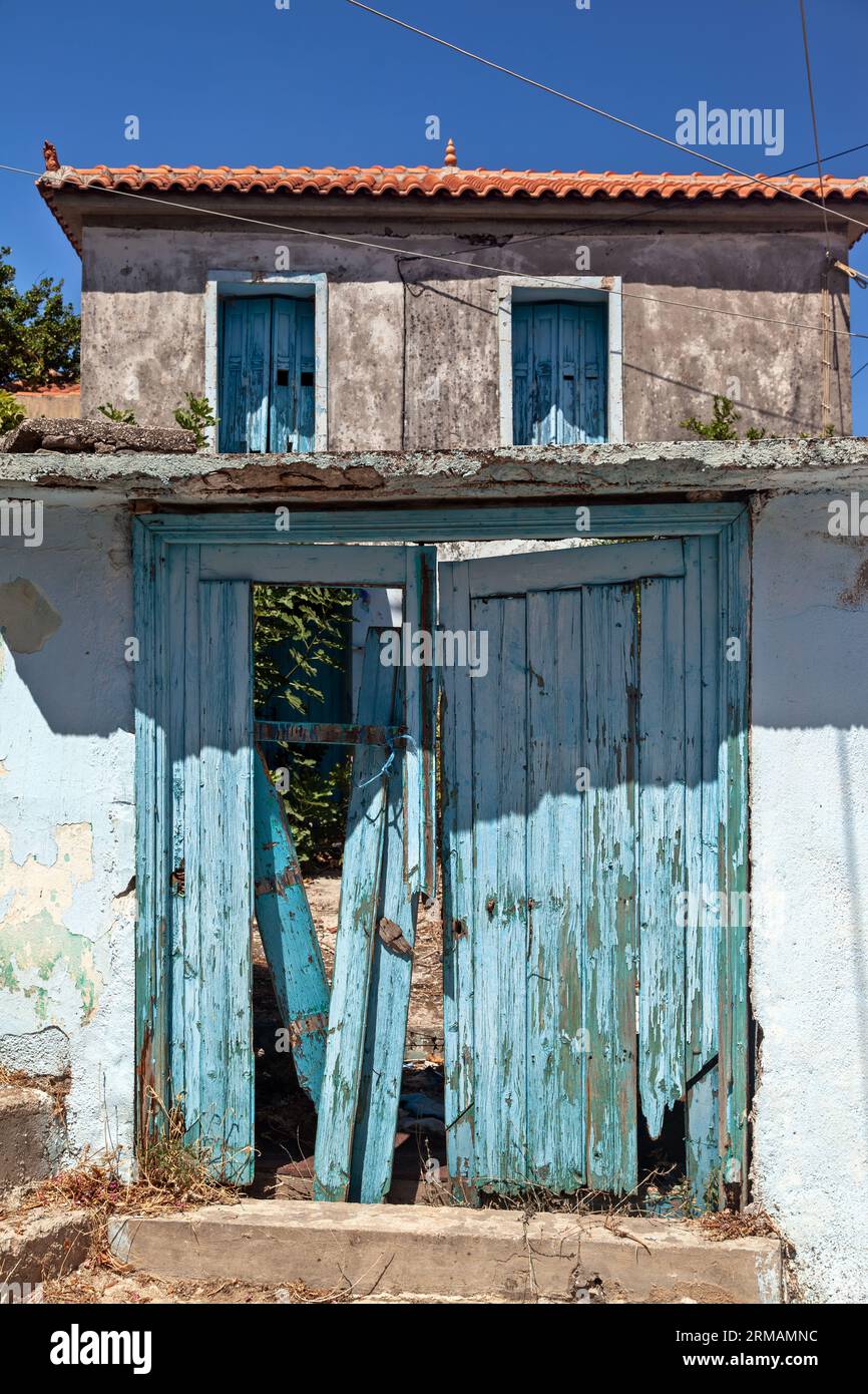 Alte traditionelle hellblaue Holztür eines verlassenen Hauses, vor einem moderneren Haus, im malerischen Dorf Chidira in Lesbos, Griechenland Stockfoto