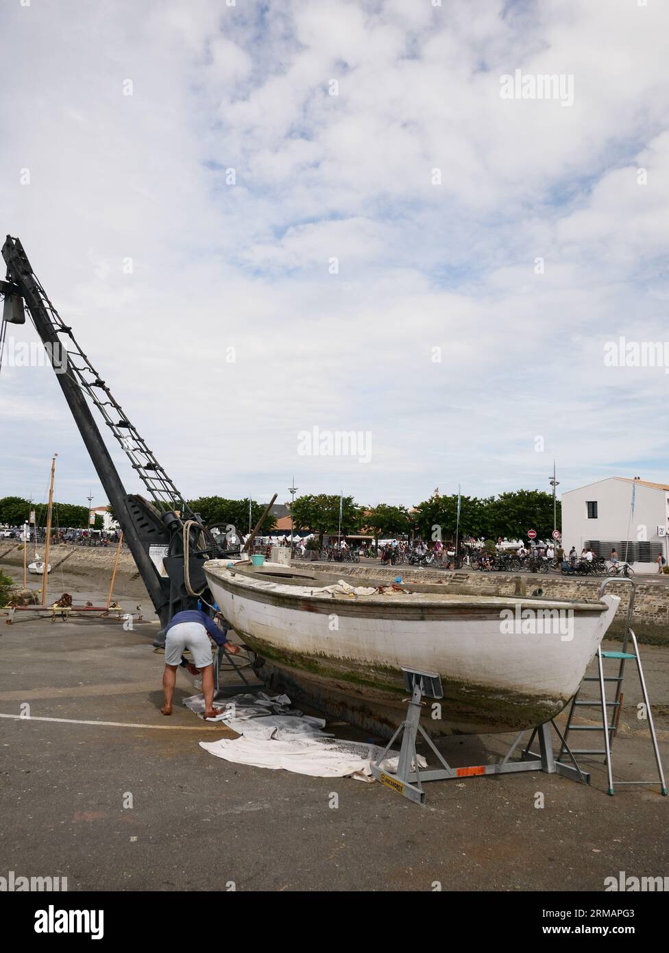 Mann, der an der Bootswartung arbeitet, Hafen von Noirmoutier en i'Ile bei Ebbe. Noirmoutier, Vendee, Frankreich Stockfoto