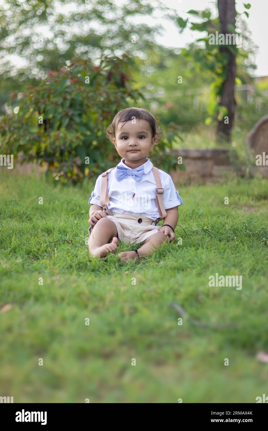 Isoliertes süßes Kleinkind mit unschuldigem Gesichtsausdruck im Freien aus verschiedenen Blickwinkeln am Tag Stockfoto