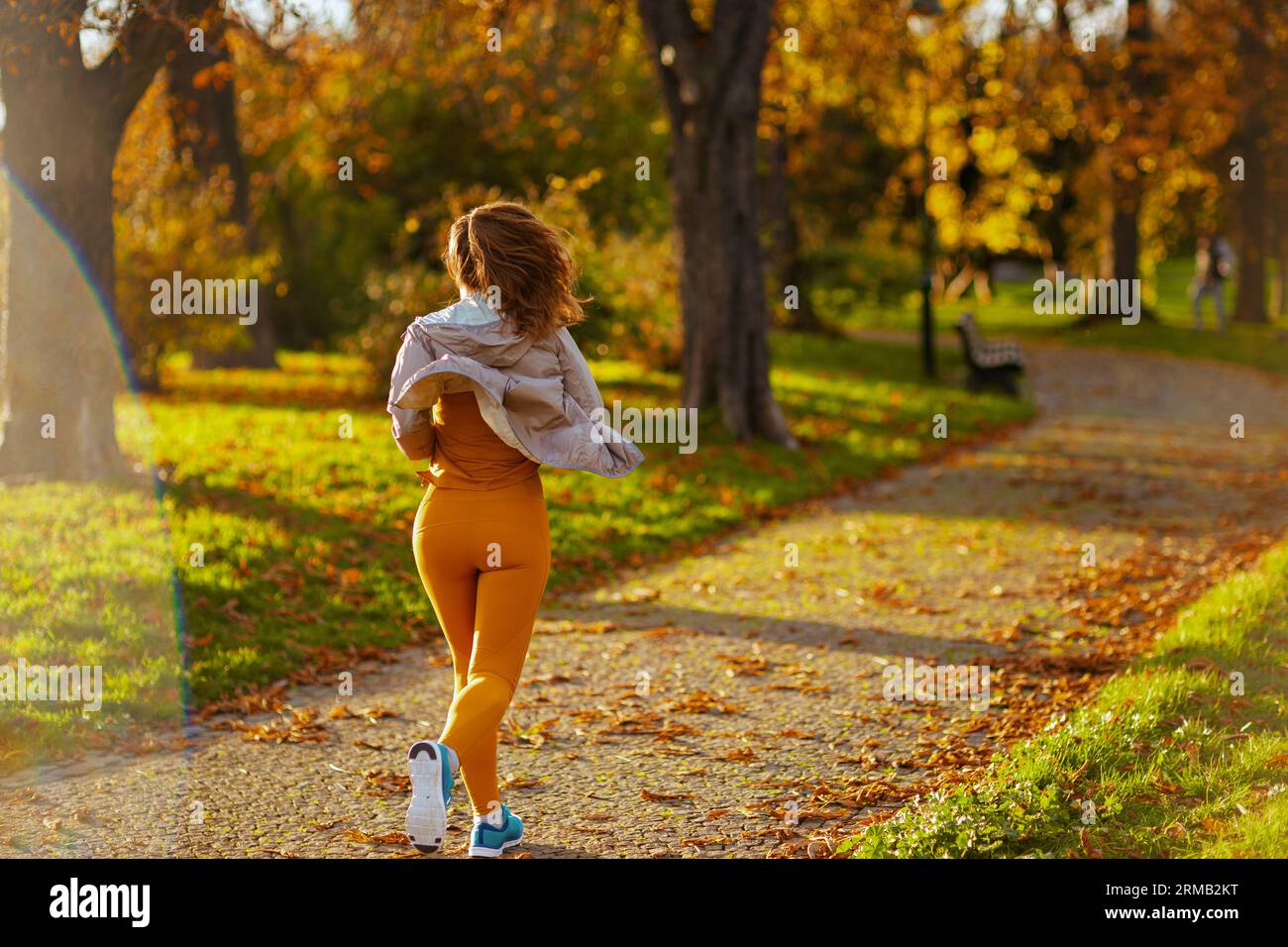 Hello autumn. Seen from behind female in fitness clothes in the park running. Stockfoto