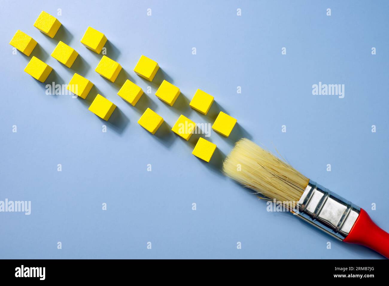 Ein Pinsel und gelbe Würfel wie Farbe. Kreative moderne Kunst Stockfoto