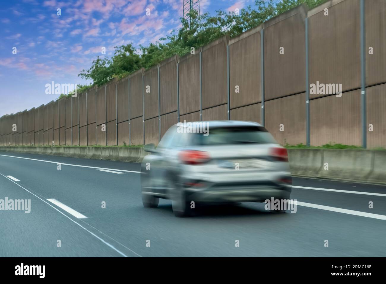 Verschwommene Autos im schallabsorbierenden Tunnel auf der Asphaltstraße. Metallstruktur mit Kunststoffteilen. Stockfoto