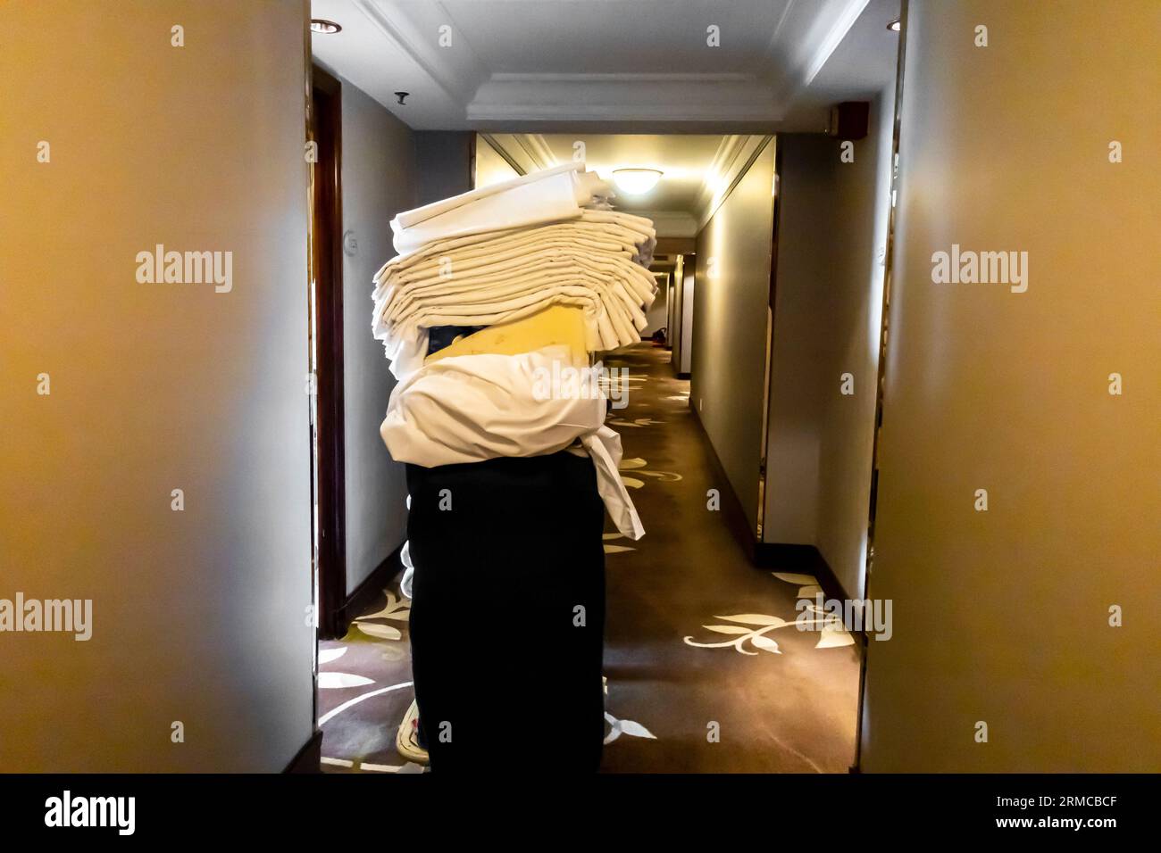 Housekeeping-Wagen mit benutzten und frischen Bettwäsche, benutzte Bettwäsche in einem Hotelflur. Reinigung Gastfreundschaft Housekeeping Trolley im Flur in der Nähe der Zimmer Stockfoto