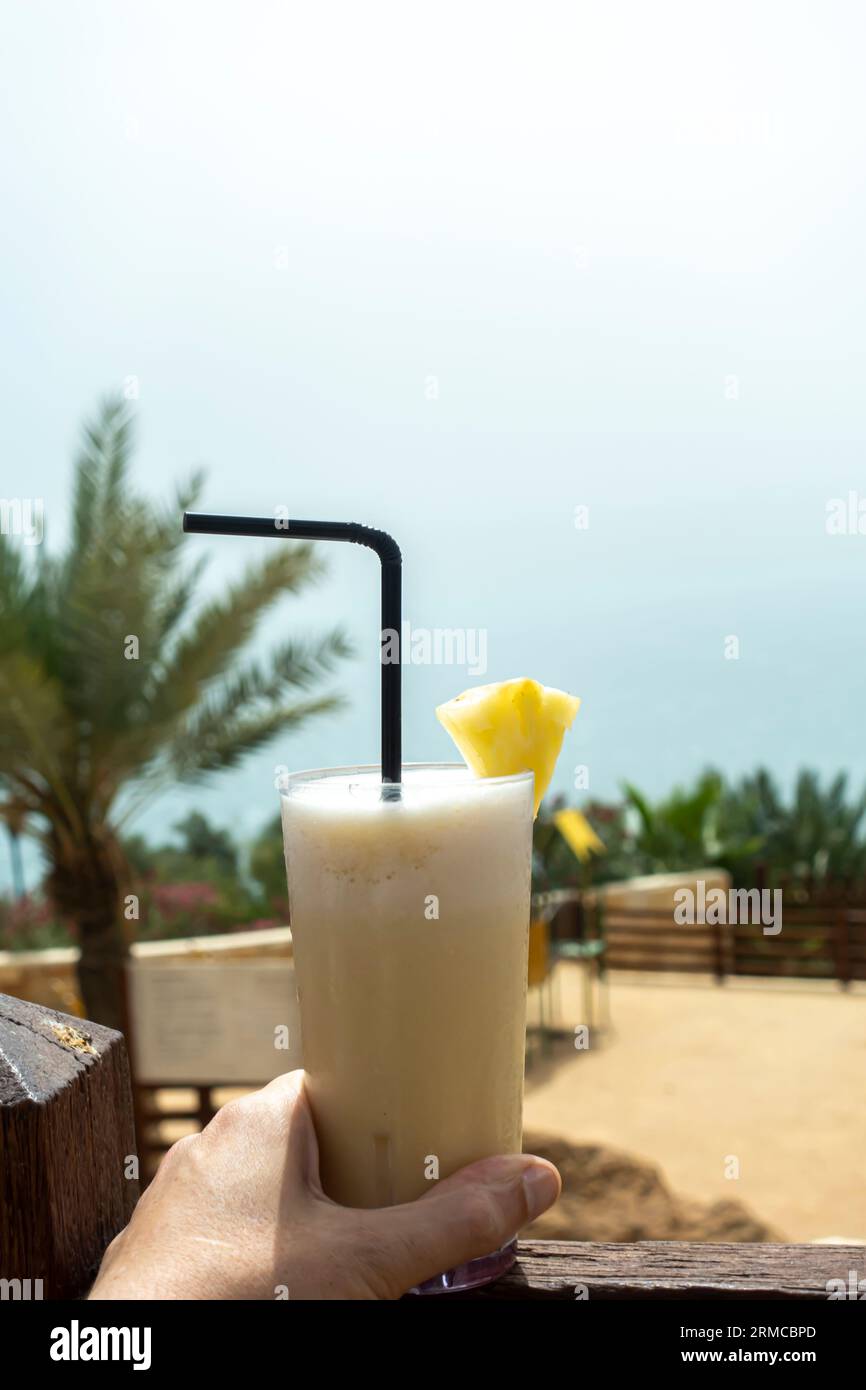 Ein Getränk der Jungfrau Piña Colada in der Hand im Glas mit Stroh, tropischem Hintergrund Stockfoto