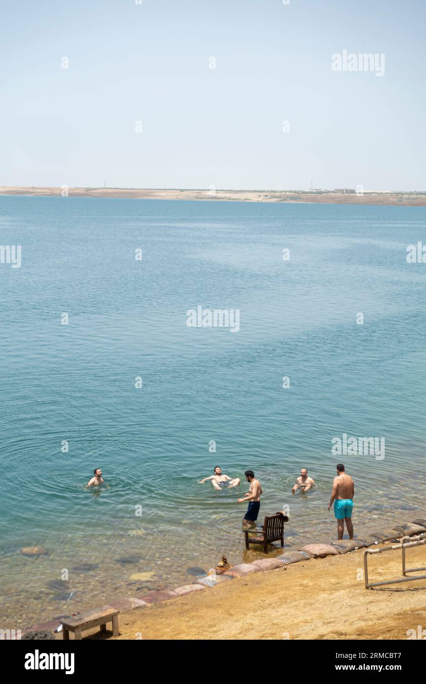 Touristen an der Küste des Toten Meeres in der schwimmenden Sperrzone, Leute, die mit Schlamm bedeckt sind, bereit, im Toten Meer, Jordanien, zu schwimmen Stockfoto