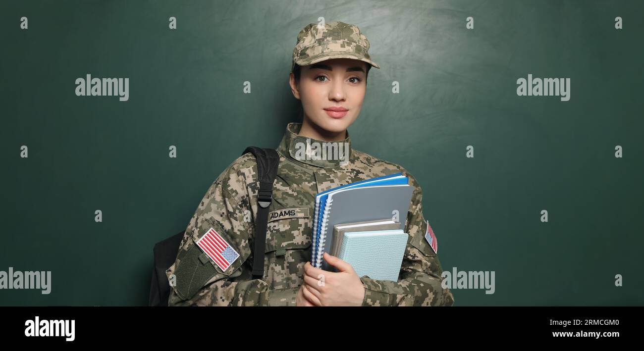 Militärische Erziehung. Kadett mit Rucksack und Notizbüchern in der Nähe des grünen Schwarzen Brettes Stockfoto