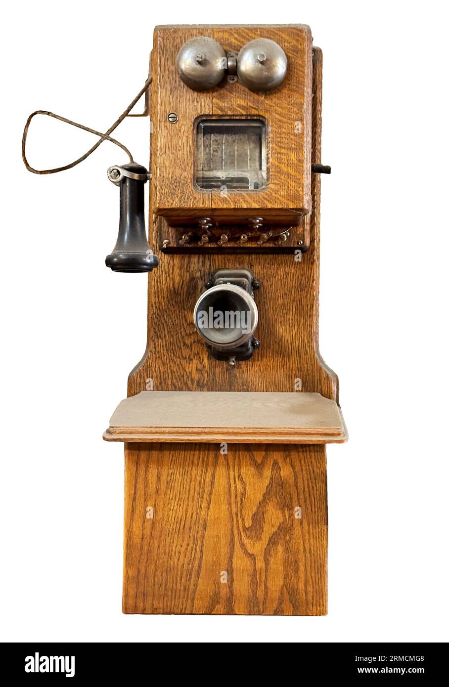 Antikes Wandtelefon in Eichenholzschrank mit Mundstück, Ohrstöpseln und zwei Glocken für das Klingelgerät. Sehen Sie sich die isolierte Nahaufnahme direkt vor dem Telefon an. Stockfoto