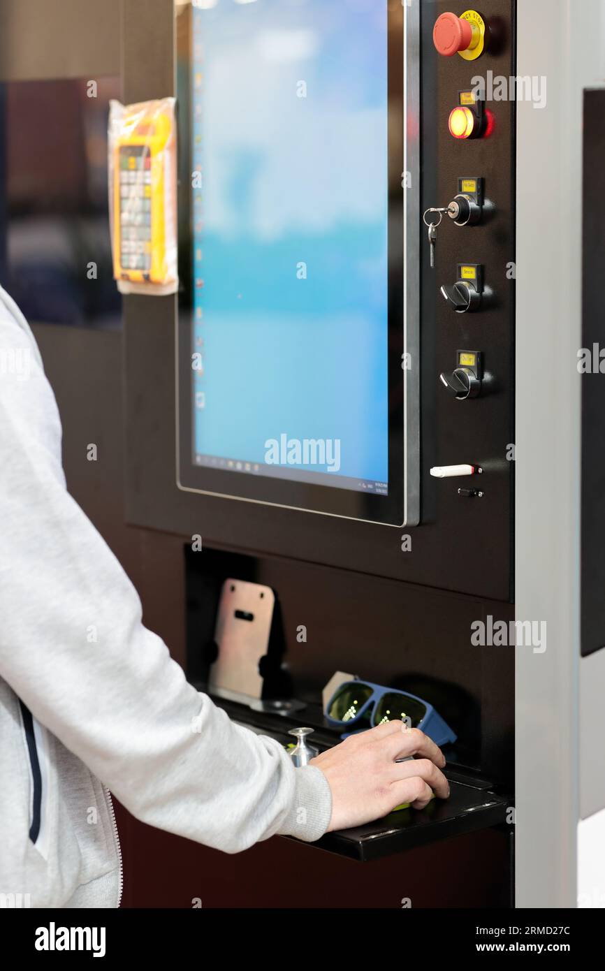Bediener an der Bedienkonsole der CNC-Laserschneidmaschine. Selektiver Fokus. Stockfoto