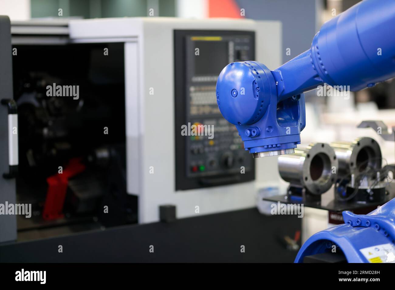 Roboter und die CNC-Drehmaschine. Automatisierte robotische Arbeitszelle. Selektiver Fokus. Stockfoto