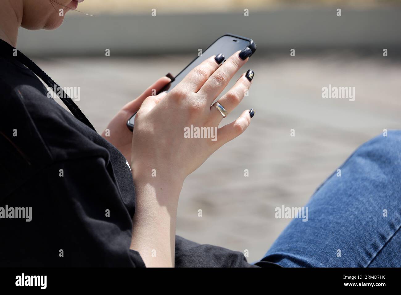Frau sitzt mit Smartphone auf einer Straße. Mobile Kommunikation in der Stadt Stockfoto