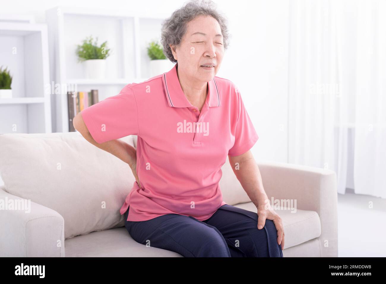 Ältere Frau mit Rückenbeschwerden zu Hause Stockfoto