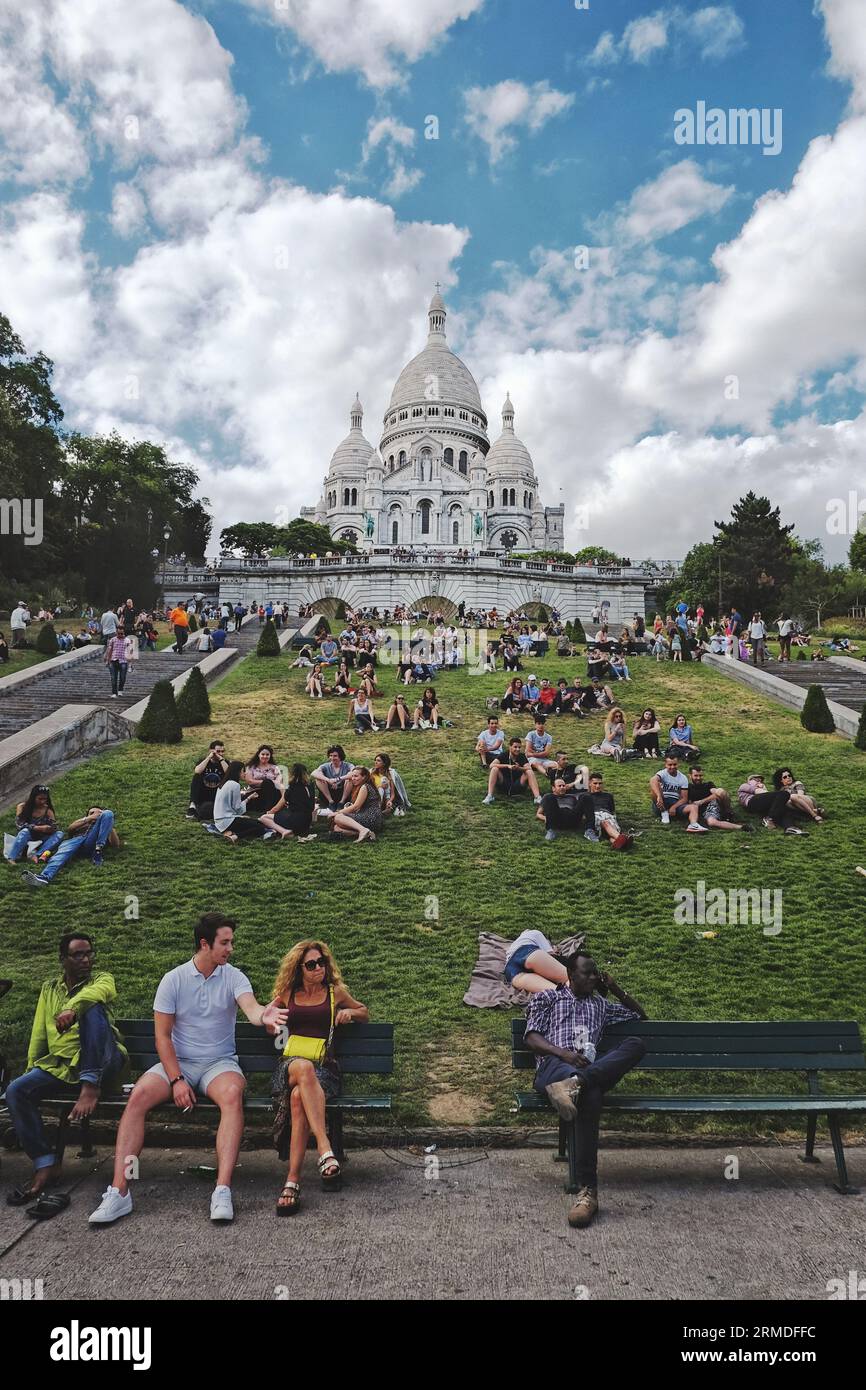 Platz Louise Michel Menschen genießen einen Sommertag in Paris sitzen auf dem Gras mit der Basilika Sacré-Cœur de Montmartre im Hintergrund Stockfoto