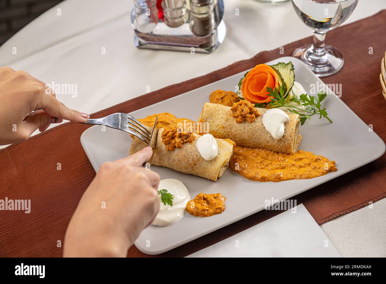 Pfannkuchenrolle mit Fleischfüllung, serviert in Sauerrahm und Paprikasauce. Stockfoto