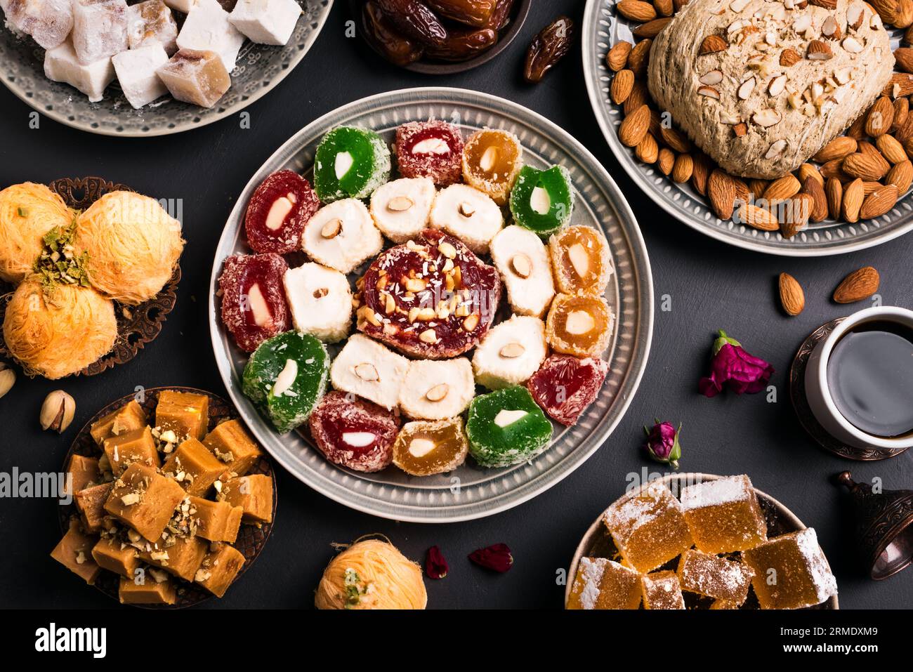 Nahöstliche Süßigkeiten, türkische Köstlichkeiten und Kaffee auf schwarzem Hintergrund. Arabisches Dessertsortiment, rahat lokum, Halva, Sherber, Pismaniye mit Nüssen und Stockfoto
