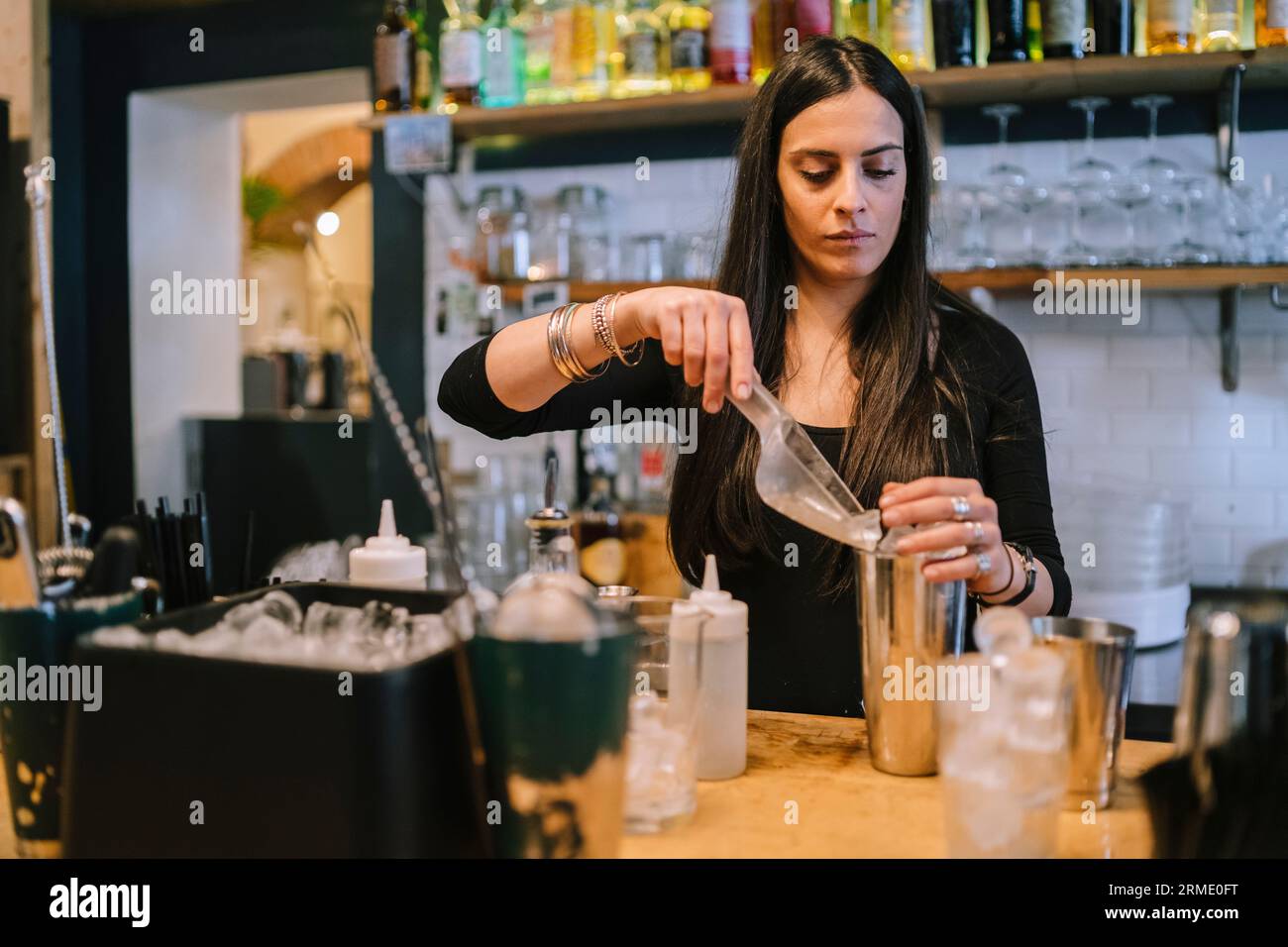 Die junge Barfrau bereitet einen alkoholischen Cocktail in der Bar zu Stockfoto