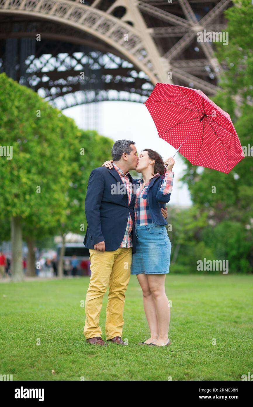 Paar mit rotem Regenschirm unter dem Eiffelturm Stockfoto