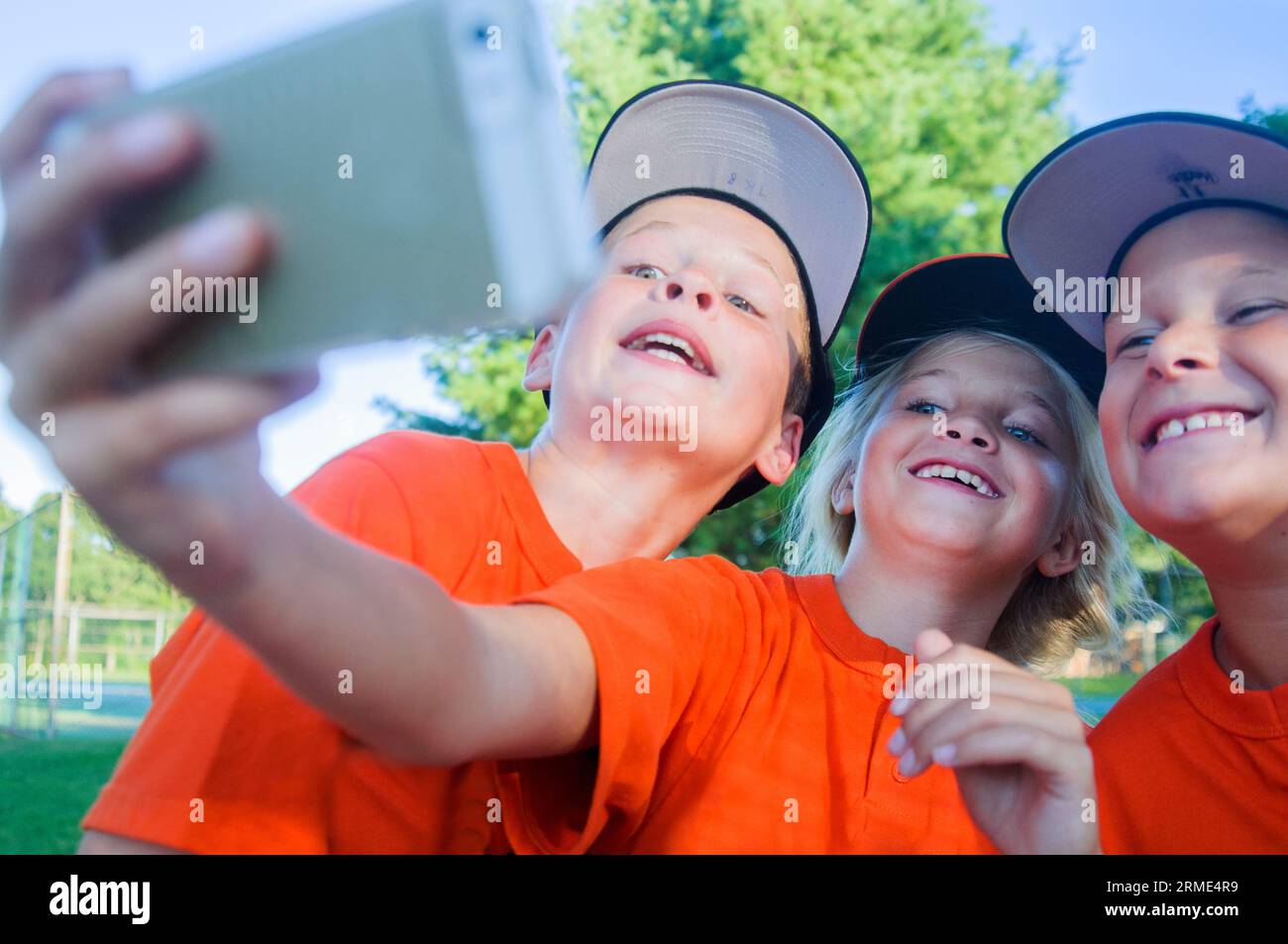 Ein 10-jähriges Mädchen im Baseballteam nimmt Selfies mit Teamkollegen auf Stockfoto