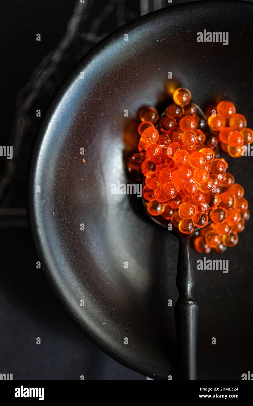 Schwarzer Löffel mit rotem Kaviar Stockfoto