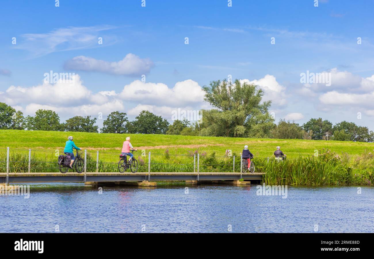 Menschen überqueren eine Brücke am Vecht auf dem Fahrrad in der Nähe von Hardenberg, Niederlande Stockfoto