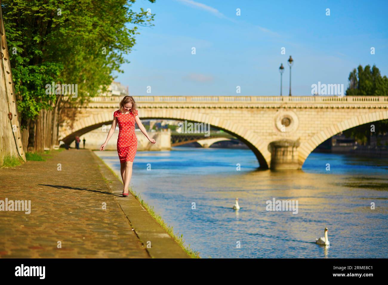 Schöne junge Frau in rotem Polka-Dot-Kleid in der Nähe der seine an einem schönen Sommertag Stockfoto