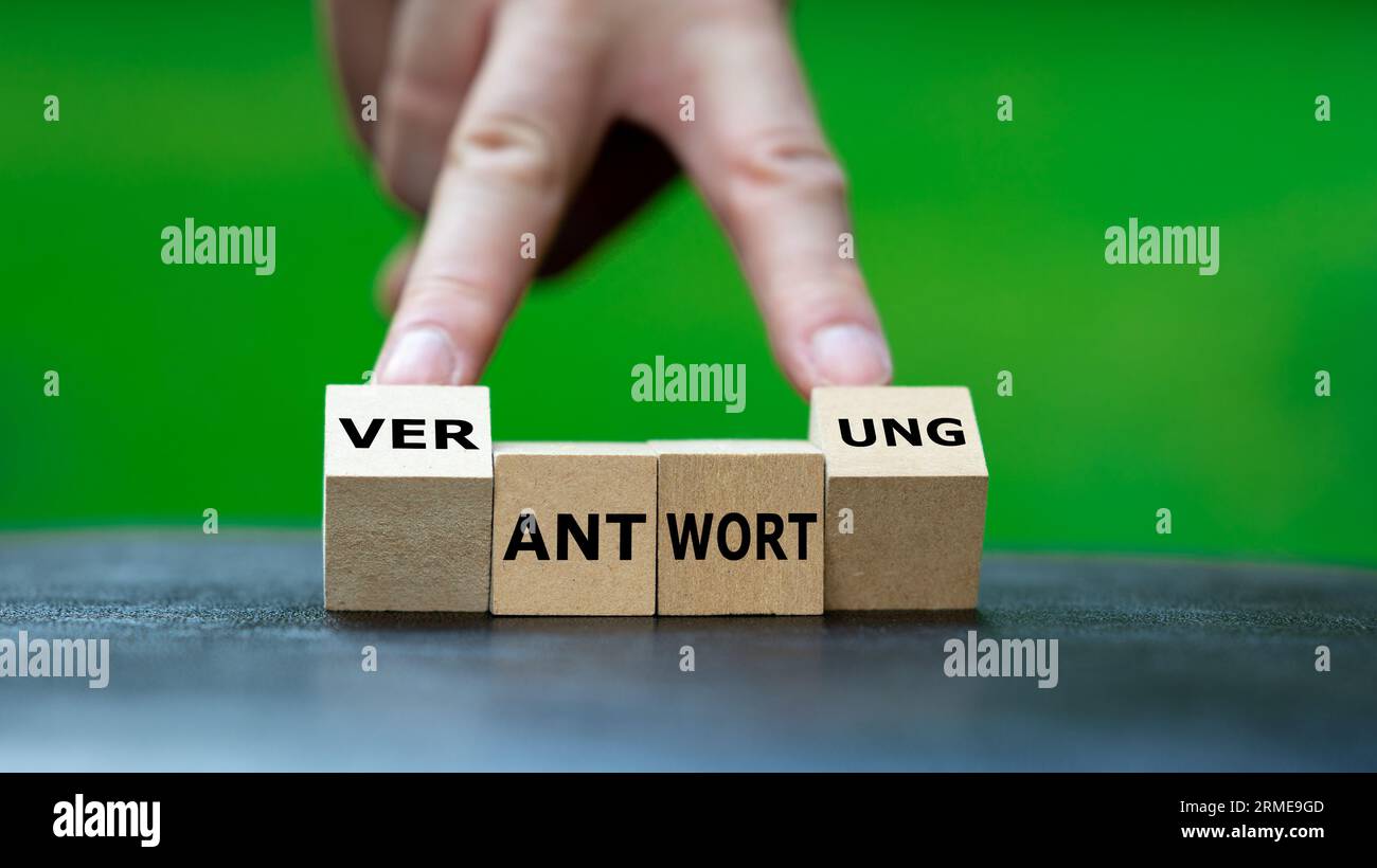Hand dreht Holzwürfel und ändert das deutsche Wort „Antwort“ in „Verantwortung“. Stockfoto