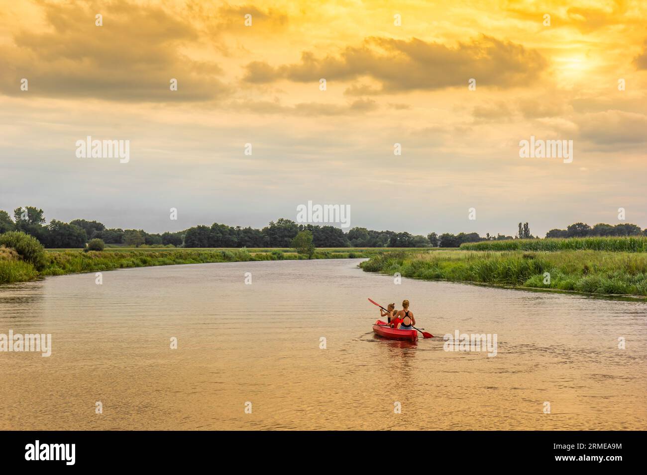 Mutter und Töchter paddeln in einem Kanu auf dem Vecht bei Sonnenuntergang in der Nähe von Hardenberg, Niederlande Stockfoto