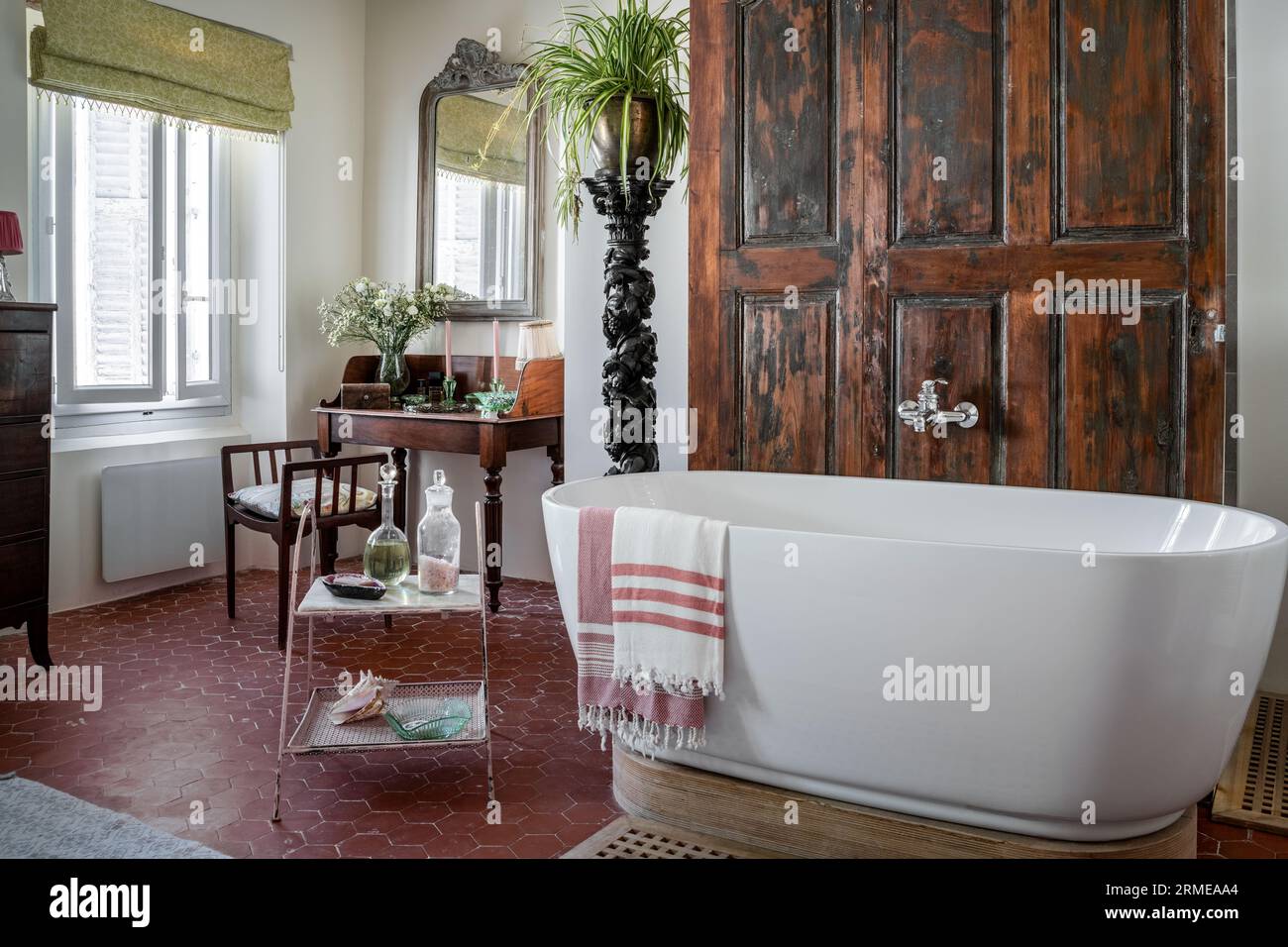 Die restaurierten Holztüren verbergen eine Dusche mit kunstvoller Fackel und einen Vintage-Waschtisch im Cotignac-Badezimmer, Var, Frankreich. Stockfoto