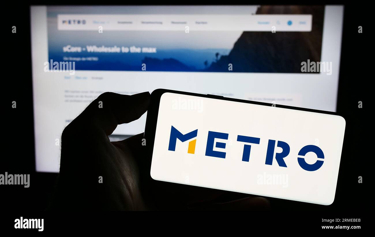 Person mit Smartphone mit Logo des deutschen Großhandelsunternehmens Metro AG auf dem Bildschirm vor der Website. Konzentrieren Sie sich auf das Display des Telefons. Stockfoto