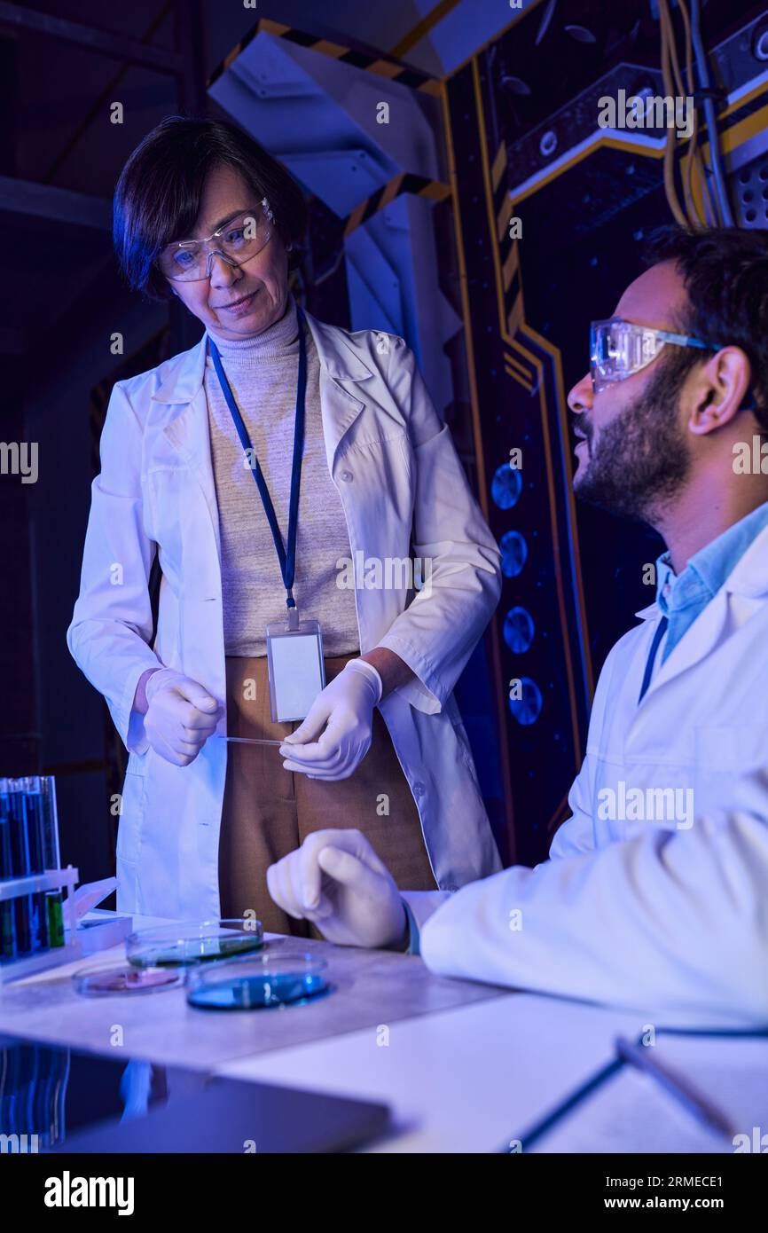 Multiethnische Wissenschaftler, die mit Petrischalen und Reagenzgläsern mit extraterrestrischen Lebensproben arbeiten Stockfoto