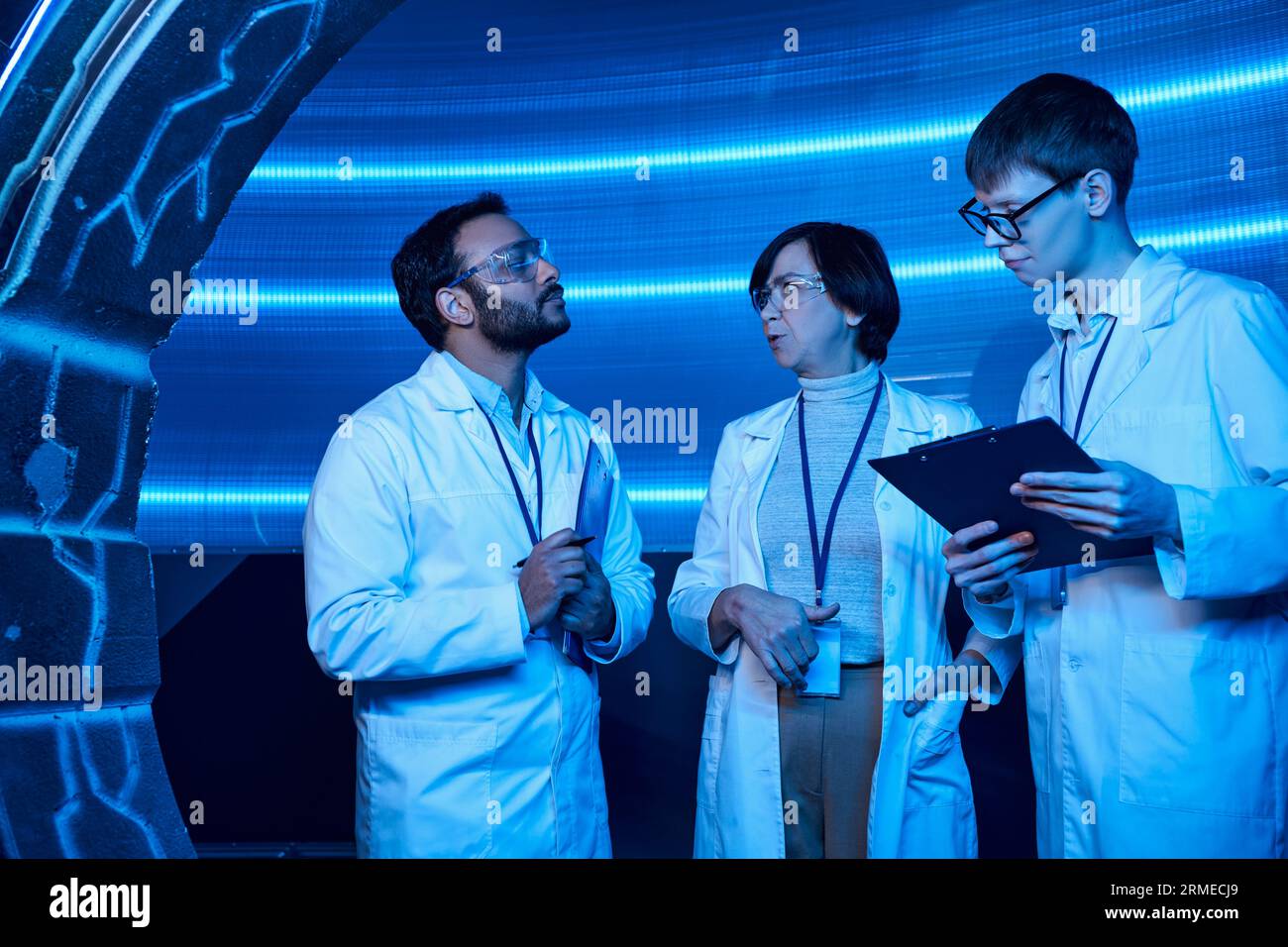 Zukunftsorientierte multiethnische Wissenschaftler, die in der Nähe junger Praktikanten im Innovationszentrum sprechen Stockfoto