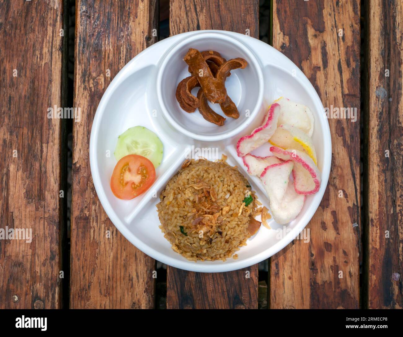 Nasi Goreng Sosis, gebratener Reis mit weißem Teller auf Holztisch. Stockfoto