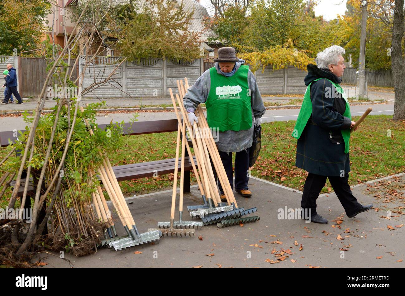 Reinigungsparks: Kommunale Kehrmaschinen stehen neben einer Reihe von Rechen, die gegen die Bank gelehnt sind. Oktober 2017. Park Nivki. Kiew, Ukraine Stockfoto