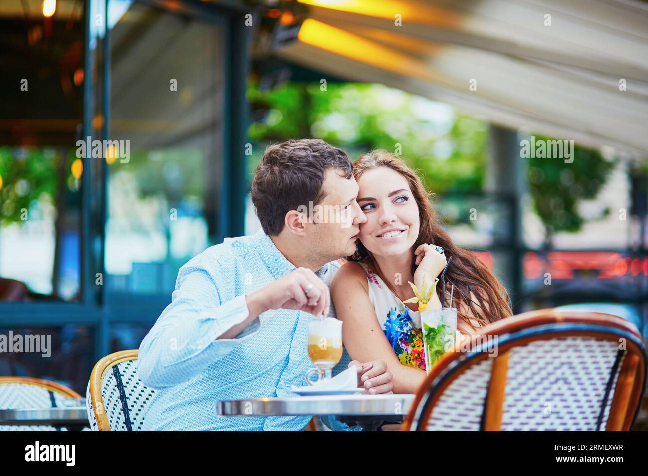 Glückliches romantisches Paar, das ein Date in einem traditionellen Pariser Café hat, Kaffee und Cocktails trinkt. Touristen, die ihren Urlaub in Frankreich genießen Stockfoto