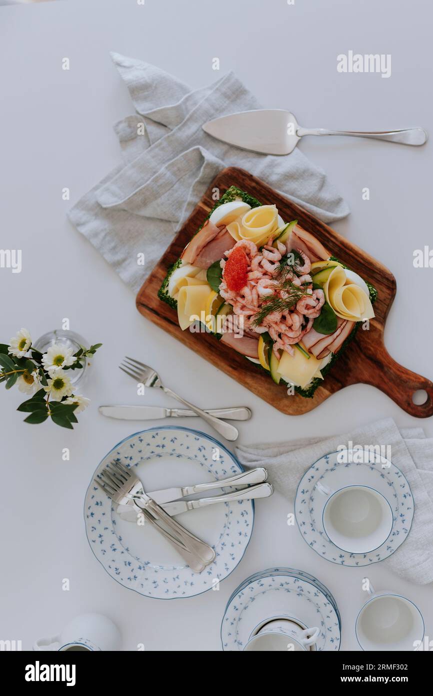 Schwedischer Sandwichkuchen mit Shrimps, Käse, Schinken und Eiern auf Holzbrett am Tisch Stockfoto