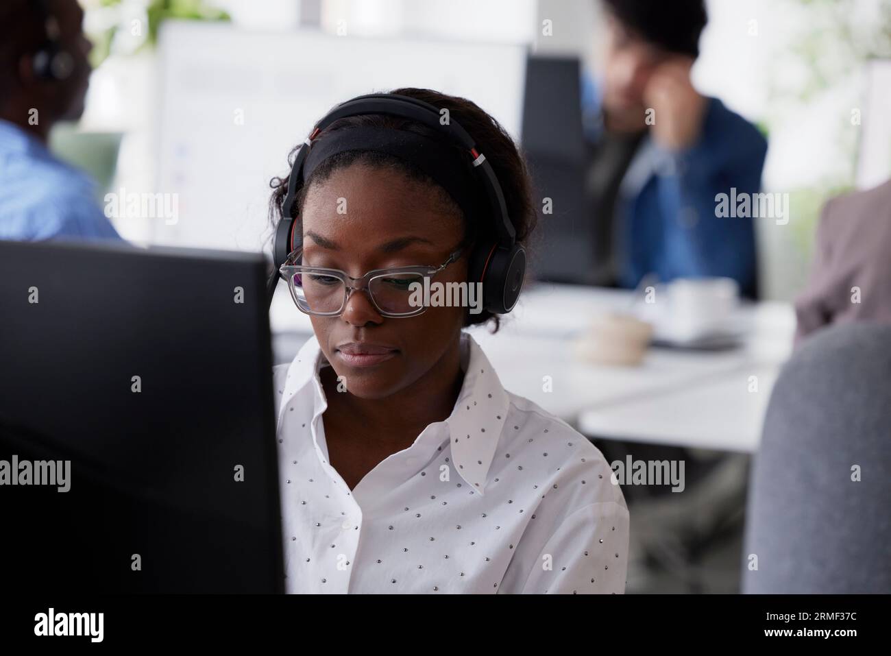 Erwachsene Frau mit Headset im Büro Stockfoto