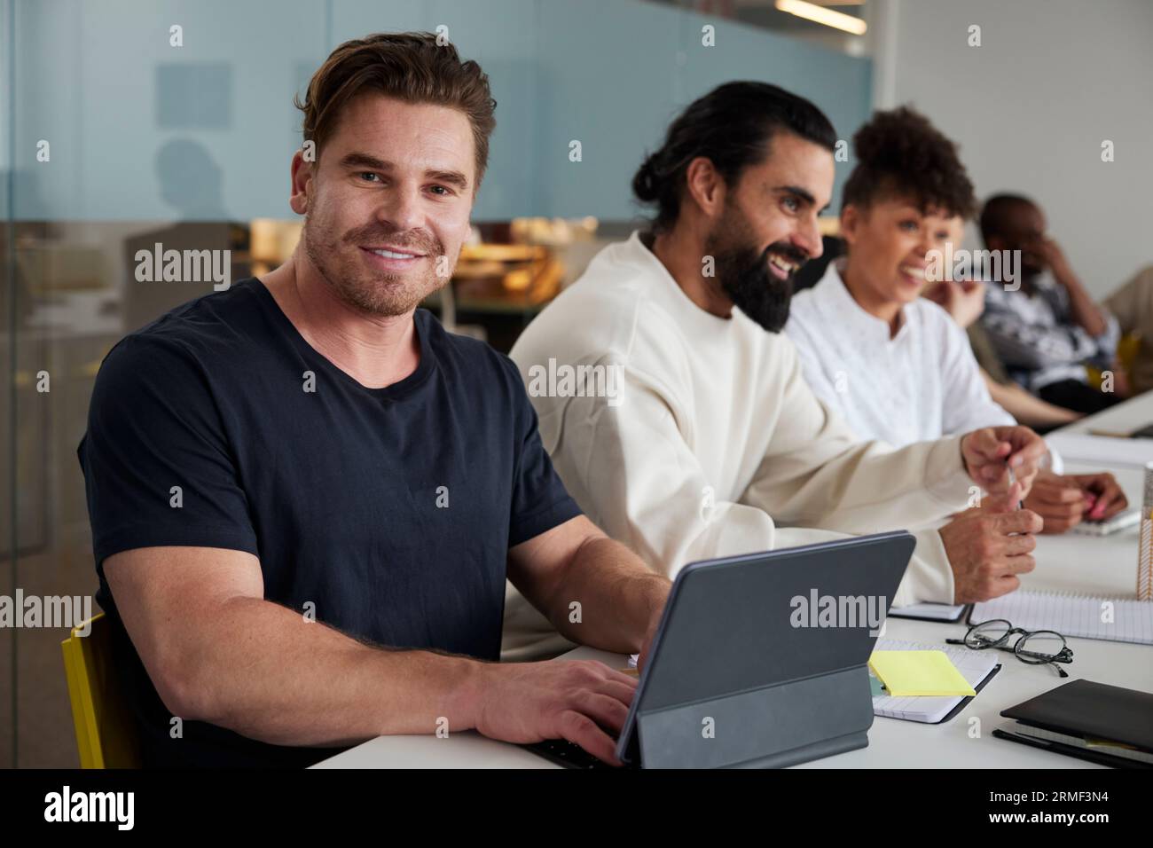 Mann sitzt auf einem Geschäftstreffen mit einem digitalen Tablet und schaut auf die Kamera Stockfoto