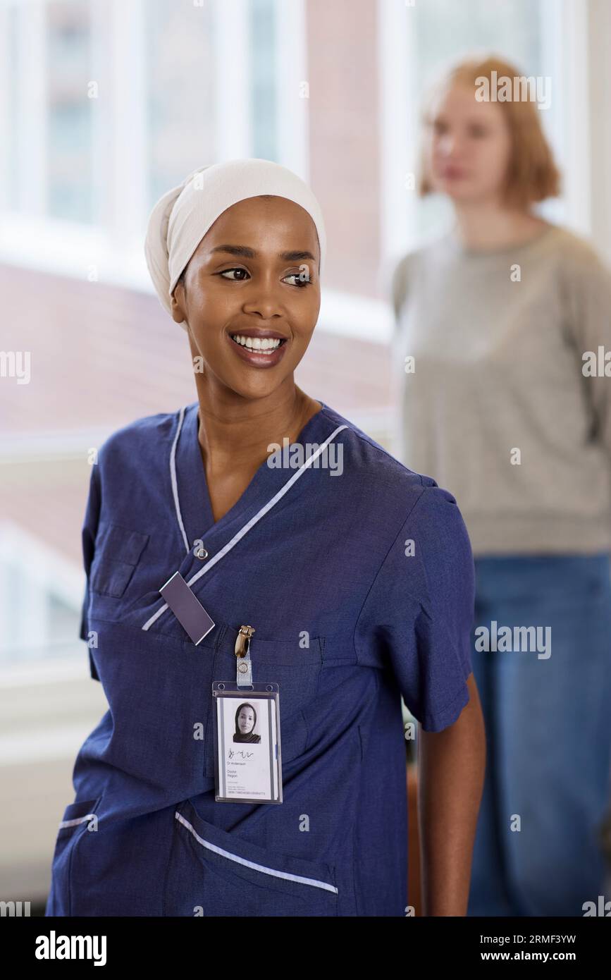 Lächelnde Ärztin im Krankenhaus, die wegschaut Stockfoto