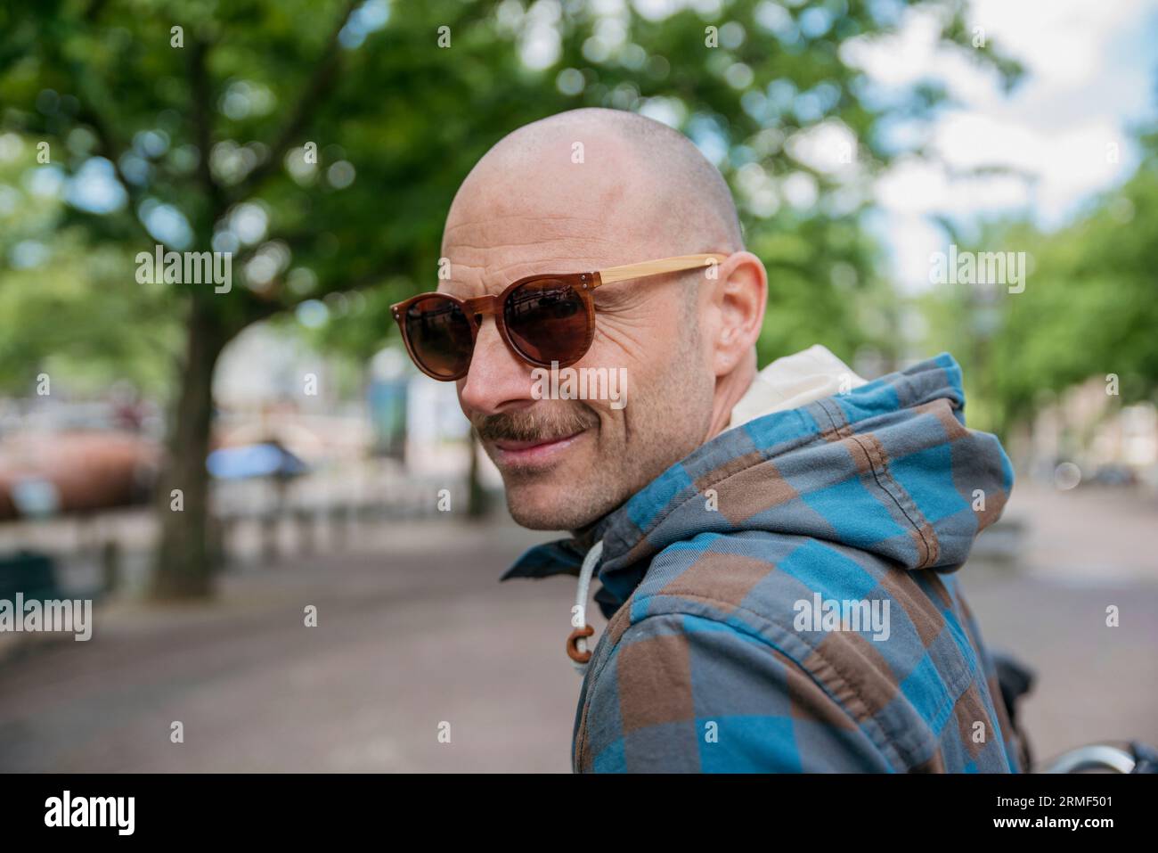 Porträt eines Glatzkopf-Mannes mit Sonnenbrille und Kapuzenhemd Stockfoto