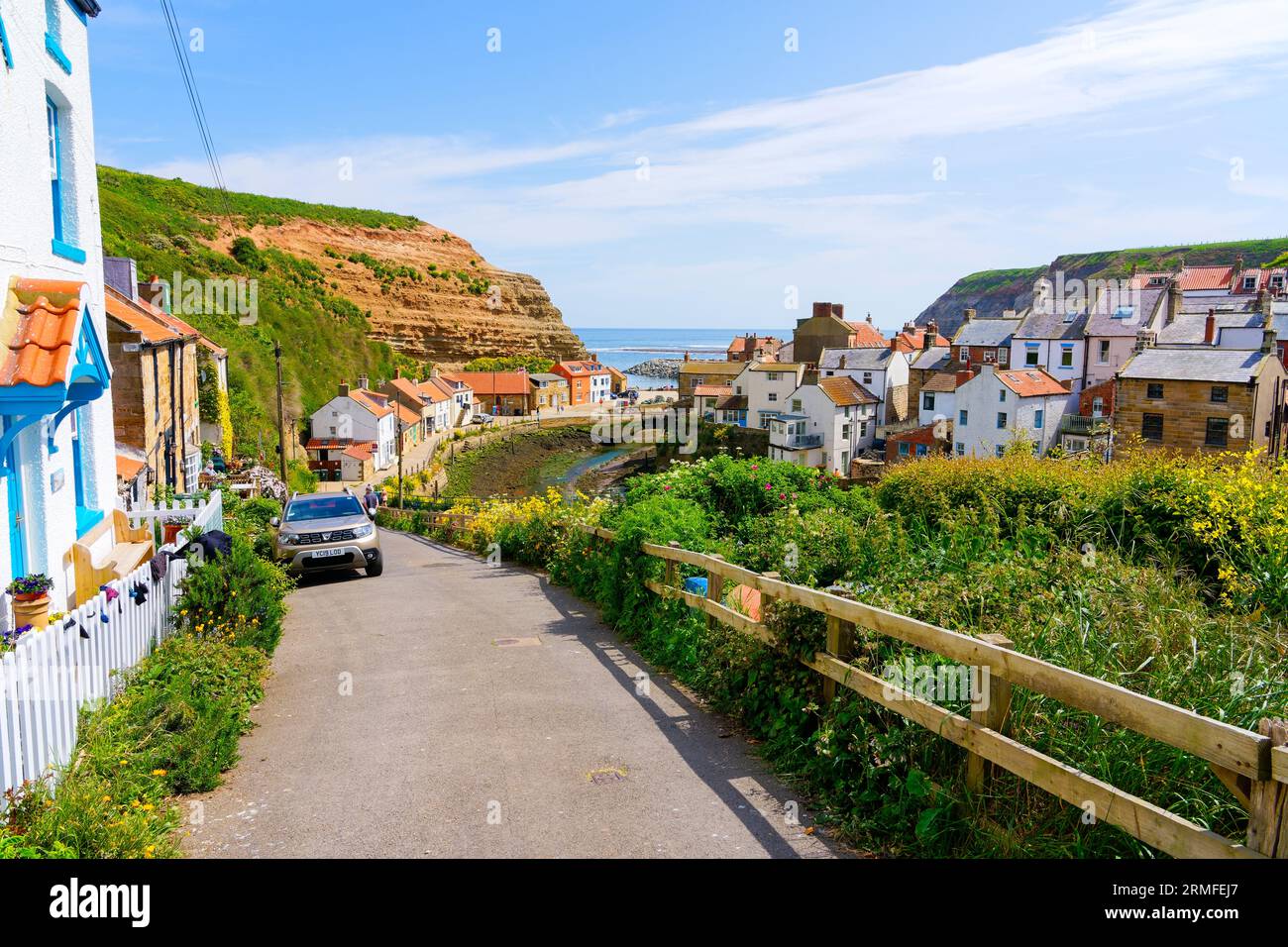 Cowbar, England - 24. Mai 2023: Steile, schmale Straße führt hinunter zum Hafen von Staithes und zur Nordsee. Stockfoto