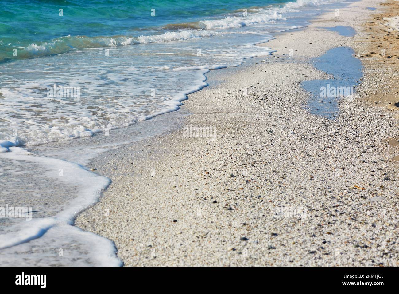 Blaues Wasser und viele weiße Körner auf dem Strand Arutas, bekannt als Reisstrand in Sardinien, Italien Stockfoto