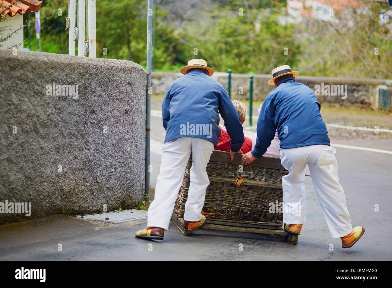 Berühmte Rodelfahrer, die den traditionellen Rohrrohrschlitten bergab auf den Straßen von Funchal, Madeira, Portugal, fahren Stockfoto