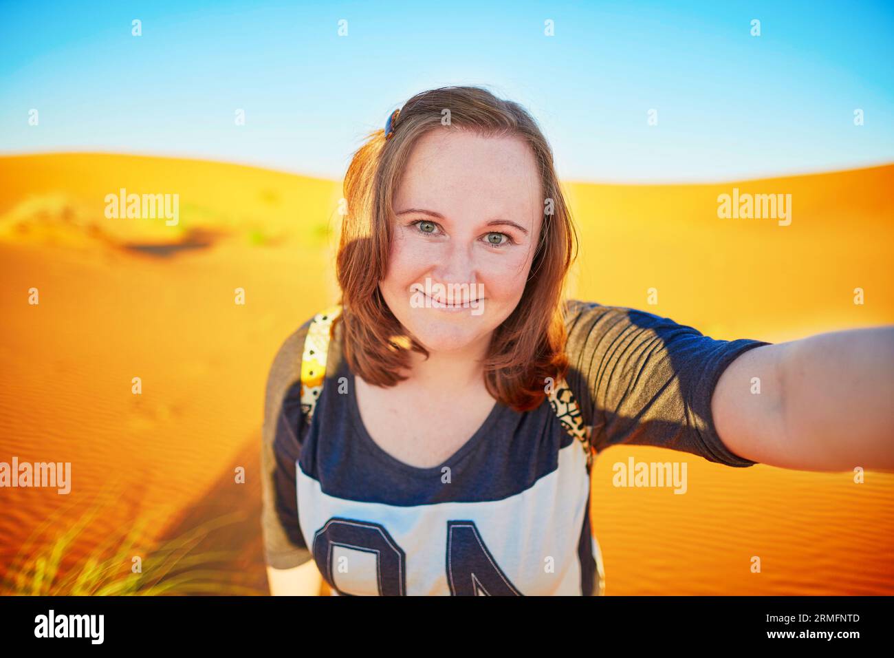 Glücklicher lächelnder Tourist, der Selfie mit Sanddünen in der Sahara nimmt, in Erg Chebby, Merzouga, Marokko Stockfoto