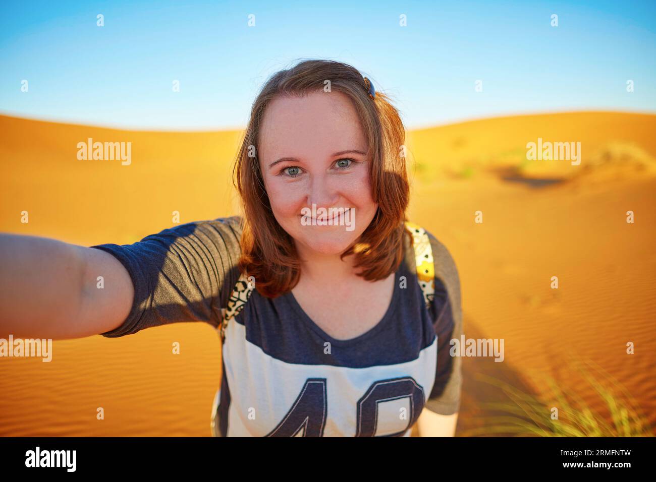 Glücklicher lächelnder Tourist, der Selfie mit Sanddünen in der Sahara nimmt, in Erg Chebby, Merzouga, Marokko Stockfoto
