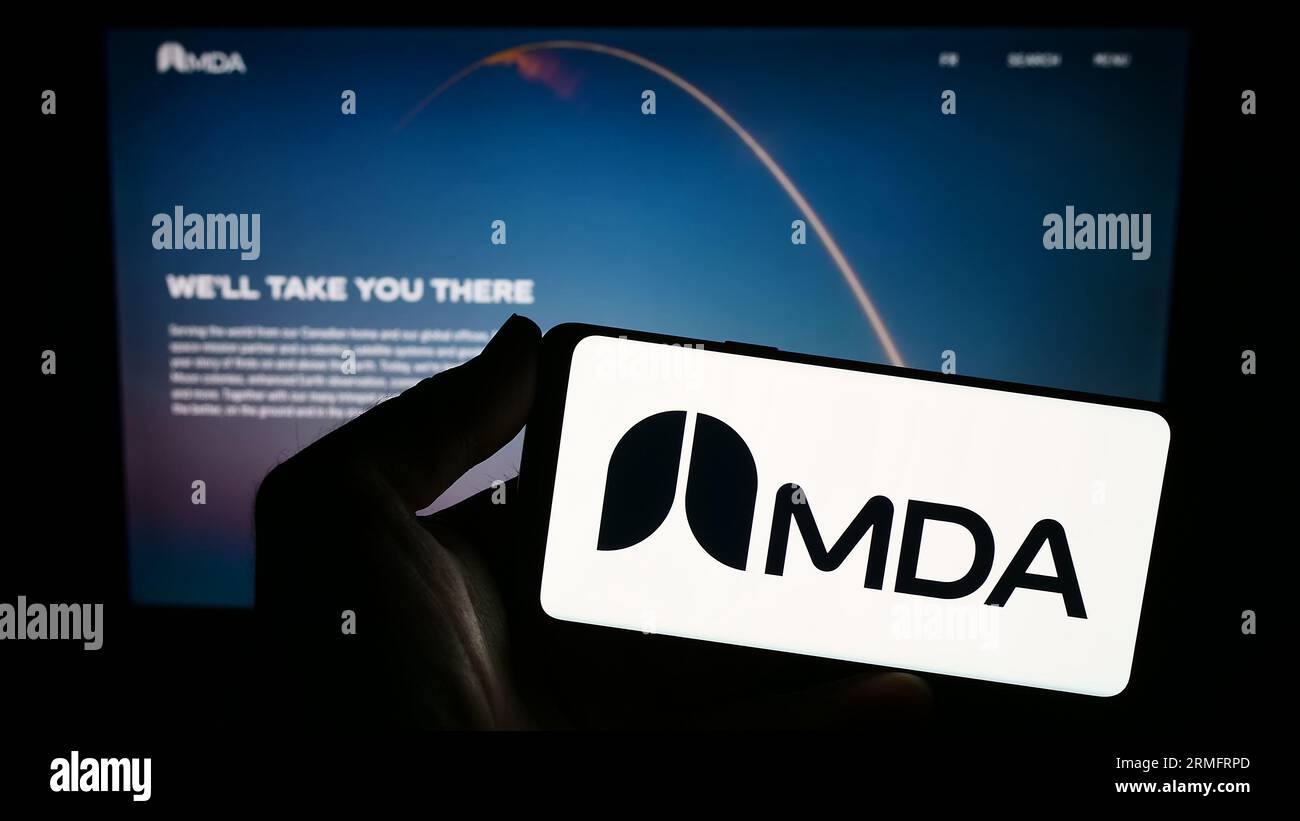 Person, die ein Smartphone mit dem Logo des kanadischen Raumfahrtunternehmens MDA Ltd. Auf dem Bildschirm vor der Website hält. Konzentrieren Sie sich auf das Display des Telefons. Stockfoto