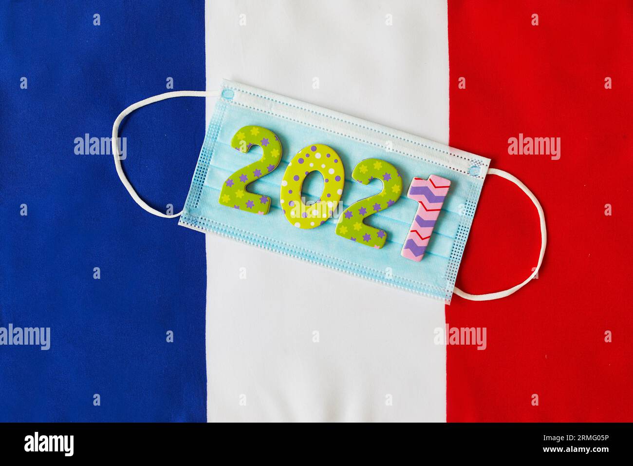 Gesichtsmaske mit 2021 Ziffern auf der französischen Flagge. Saisonale Feiertage während des Ausbruchs des Coronavirus COVID-19 in Frankreich. Quarantäne, Sperrung und soziale Netzwerke Stockfoto