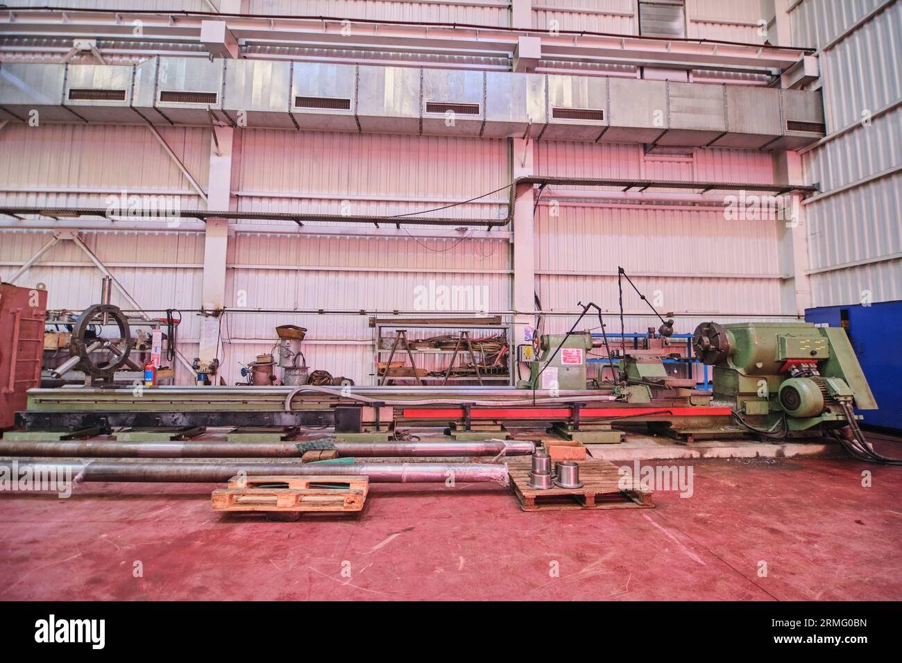 Männer, die einen Aufzug und einen Kran verwenden, um große, schwere Metallgegenstände wie Pips in einer Werkstatt/Fabrik zu bewegen. Menschen bewegen Dinge Stockfoto