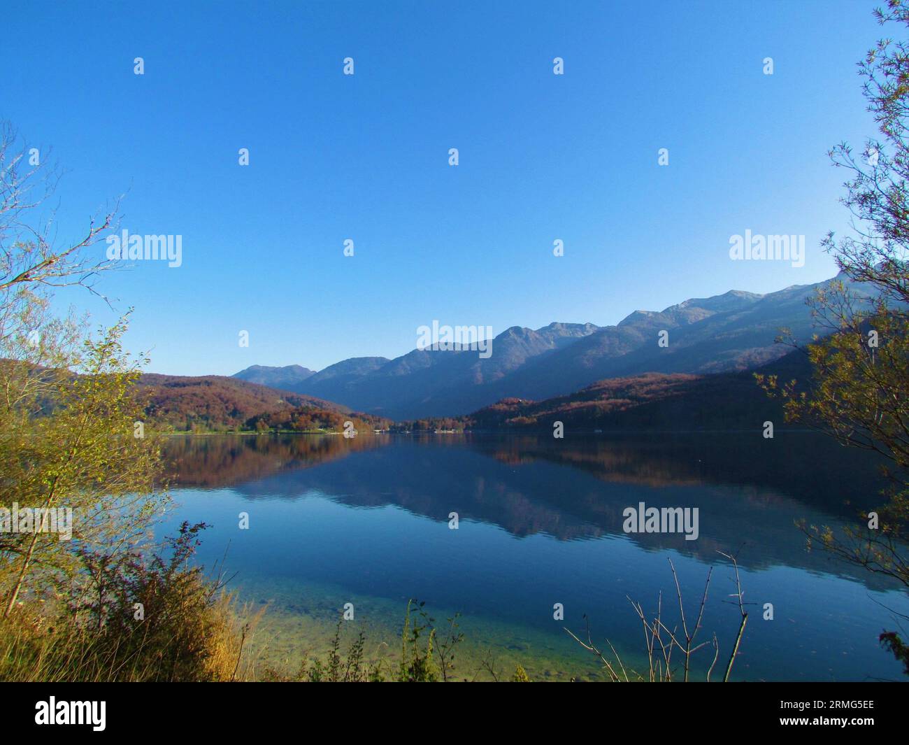 Blick auf den Bohinjer See im Spätherbst oder Herbst mit Bergkette im Rücken und Reflexion im See in der Region Gorenjska in Slowenien Stockfoto