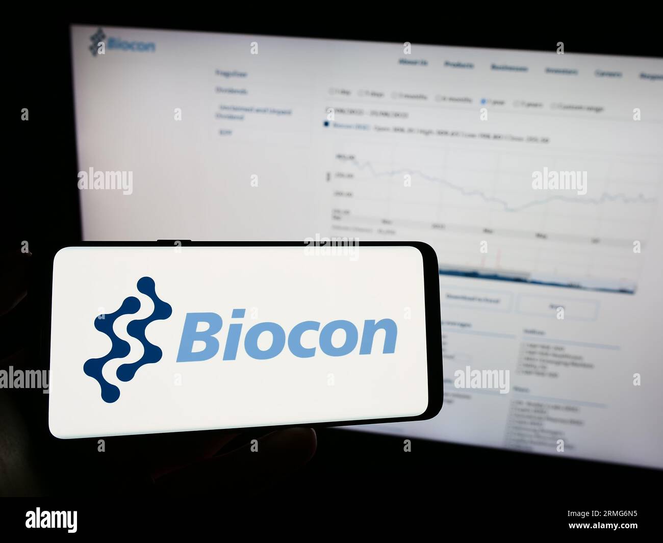 Person, die ein Mobiltelefon mit dem Logo des indischen biopharmazeutischen Unternehmens Biocon Limited auf dem Bildschirm vor der Webseite hält. Konzentrieren Sie sich auf das Display des Telefons. Stockfoto