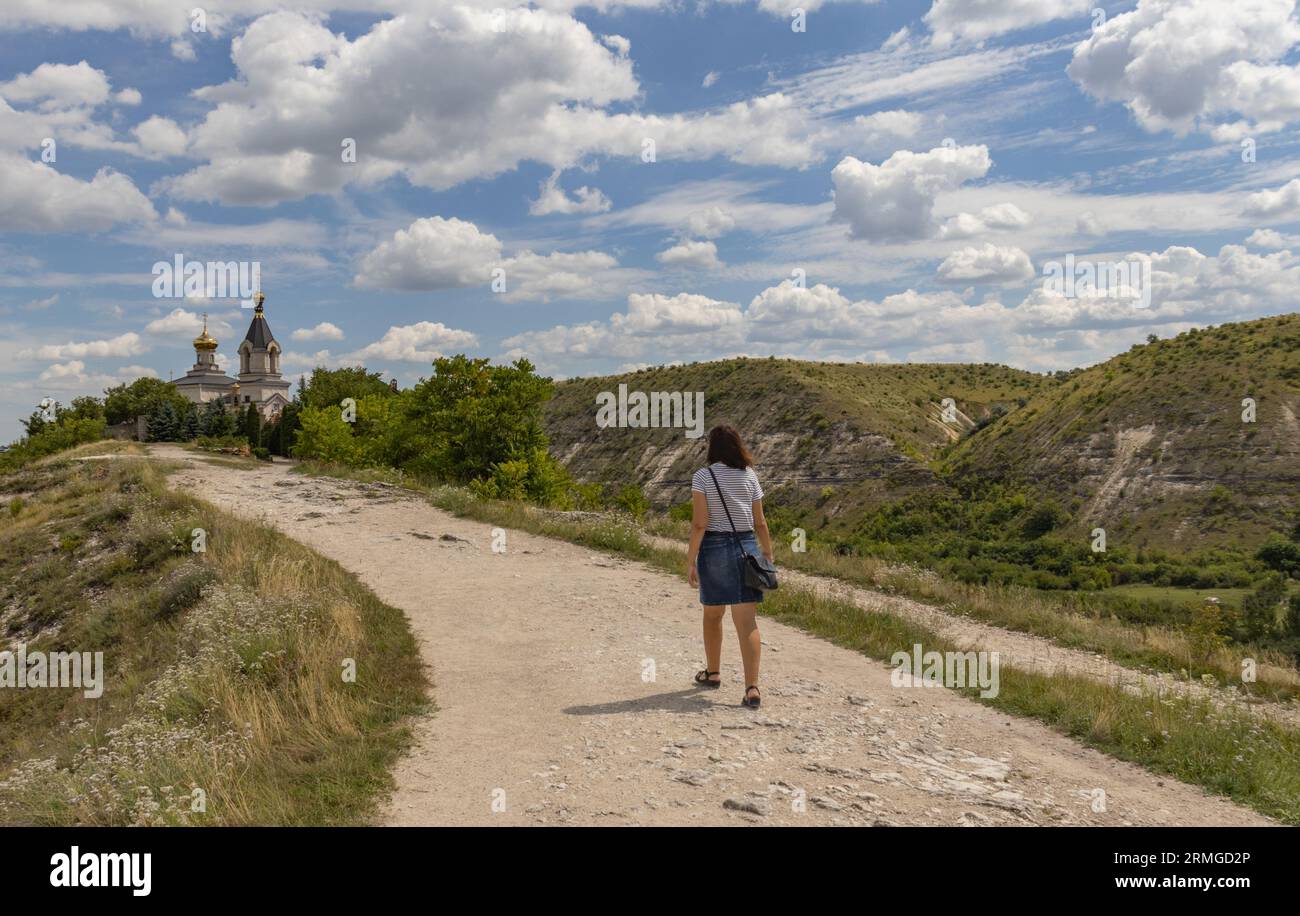 Frau, die in Richtung orthodoxe Kirche mit schöner Landschaft in Old Orhei (Orheiul Vechi), Moldawien geht Stockfoto